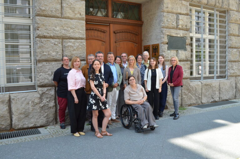 Frauen und Männer stehen aufgereiht vor einer Tür zu einem Gruppenfoto