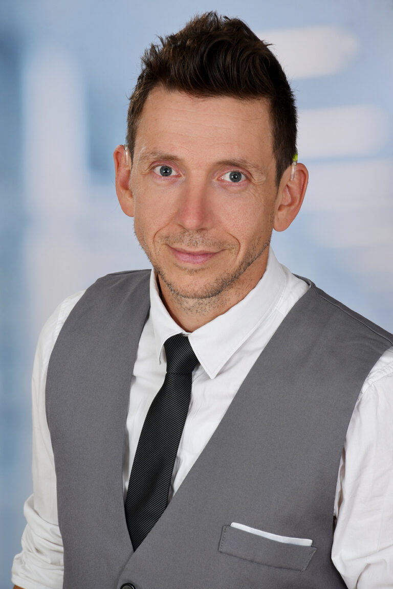 Profilbild von Oliver Hupka mit weißem Hemd, einer schwarzen Krawatte und grauer Weste
